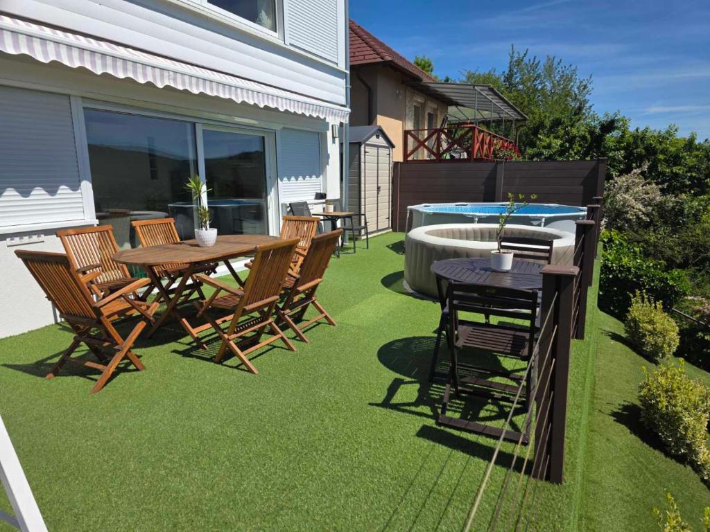 a patio with a table and chairs on grass at Dunakanyar View Apartman in Nagymaros