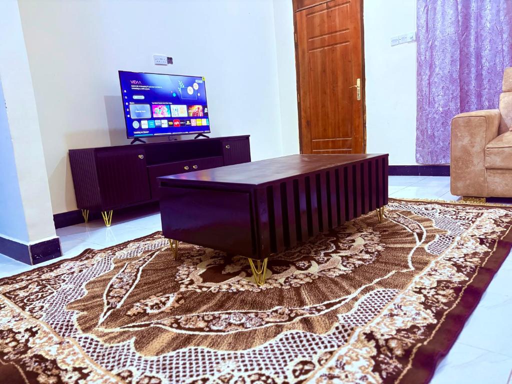 a living room with a tv and a table on a rug at Zanzibar Apartment 1 in Kibele