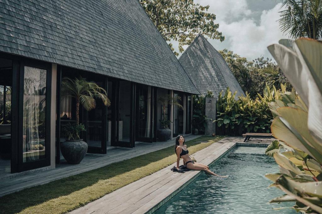 a woman sitting in a pool next to a building at MIZU Boutique Villas - Unique stay in Uluwatu in Uluwatu