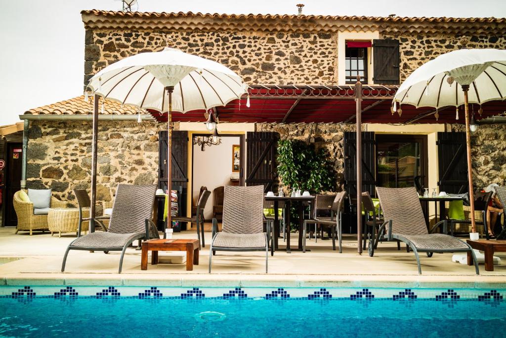 un patio avec des chaises et des parasols à côté d'une piscine dans l'établissement La Bergerie Du Cap, au Cap d'Agde