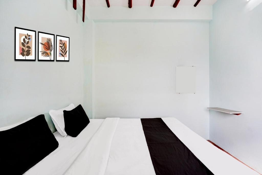 a white room with a bed with black and white pillows at HOTEL O MID STAR in Sakardarā