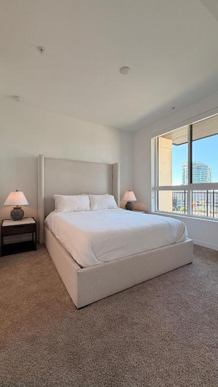 a white bedroom with a large bed and a large window at Wallace Luxurious in Los Angeles
