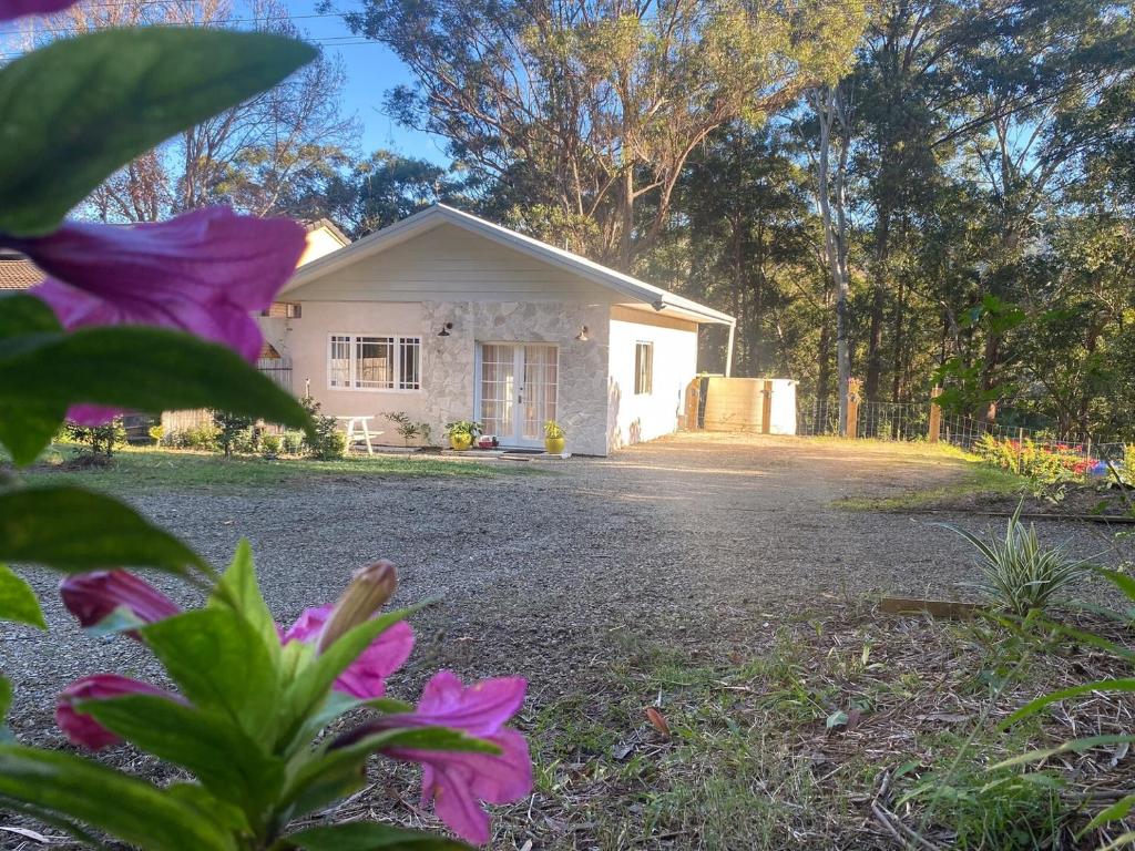 a white house with a yard with flowers at Wisteria Hideaway in Coffs Harbour