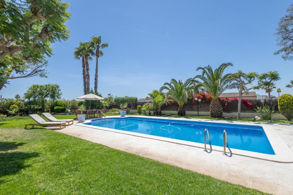 a swimming pool in a yard with palm trees at Villa las Terrenas in Calafell