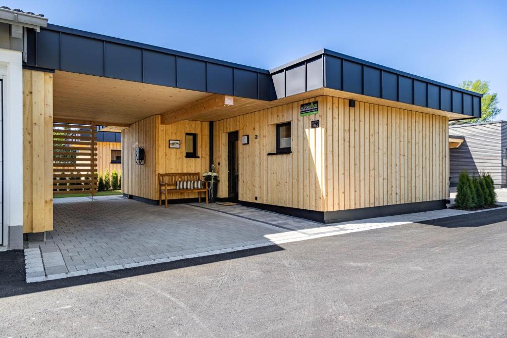 a wooden building with a black roof on a driveway at Ferienhaus Auerberg Sweet in Stötten am Auerberg