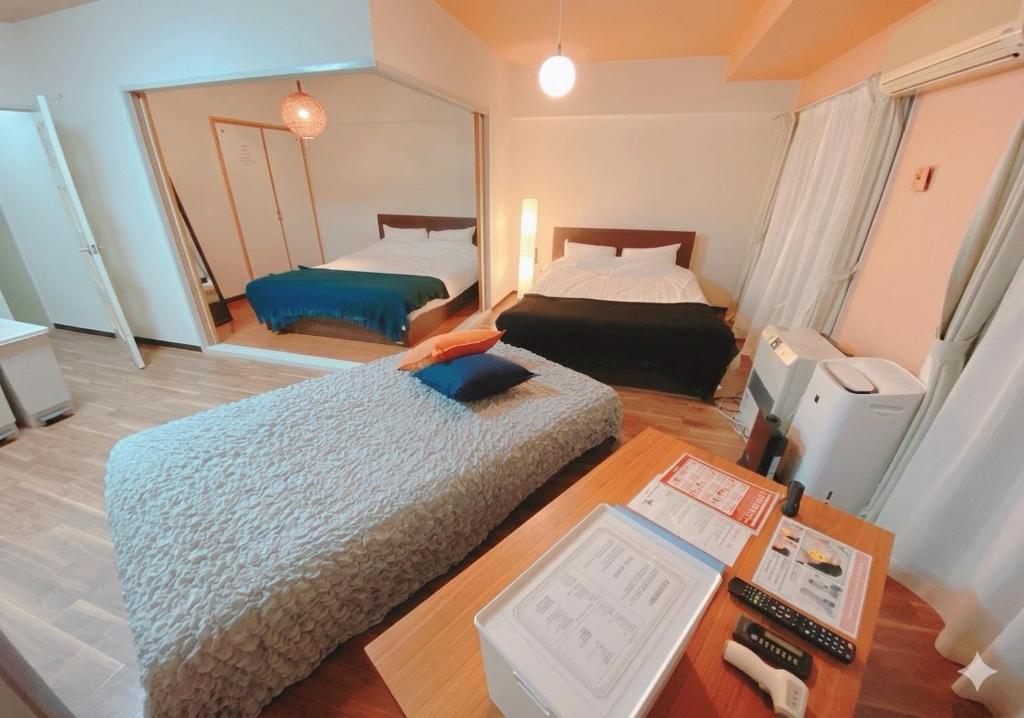 a room with two beds and a desk and a mirror at 札幌駅近 すすきの中心部 スーペリアルーム最大7名 家族やグループにお勧め 市電駅前 北海道観光食事最高立地 11歳まで子供無料 高級ベッドマットレス使用 チェックアウト11時 in Sapporo