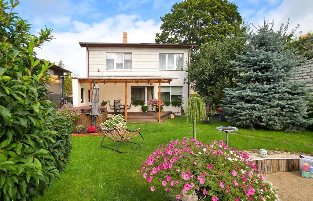 a white house with a yard with pink flowers at LULU GAST HAUS in Ventspils