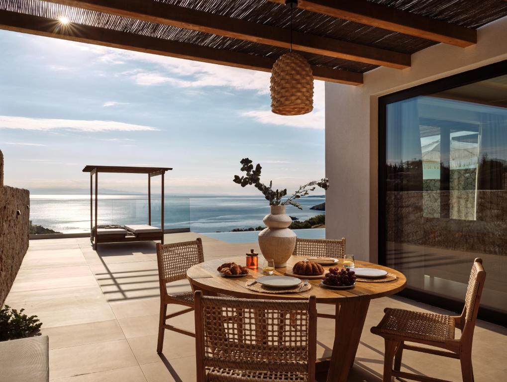a dining room with a table and chairs on a patio at Theros Luxury Suites in Agios Nikolaos