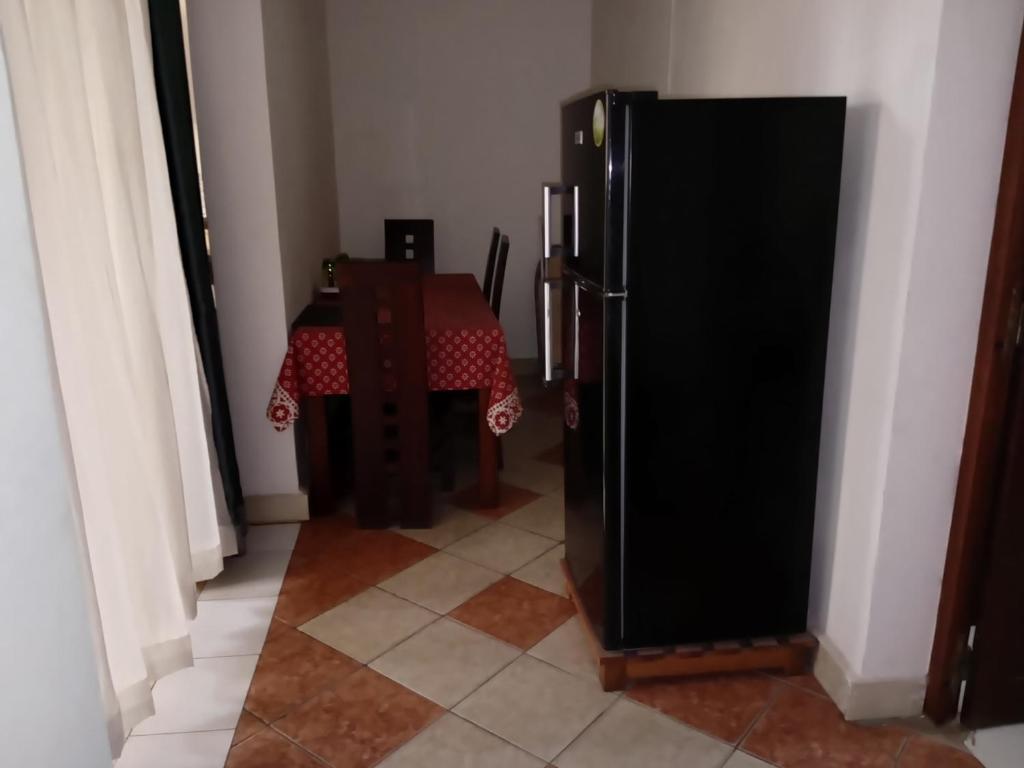 a kitchen with a table and a black refrigerator at Appart'hotel Les Capucins in Mahajanga