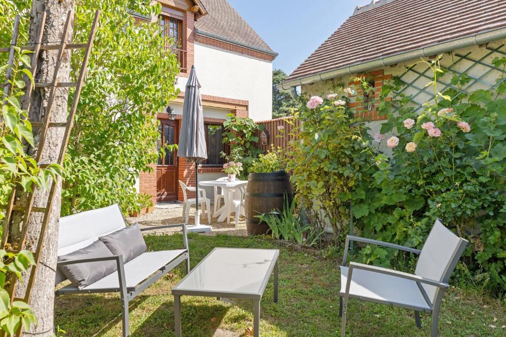 a garden with a table and chairs and an umbrella at Chambres D'hôtes 4 Saisons in Villefranche-Sur-Cher
