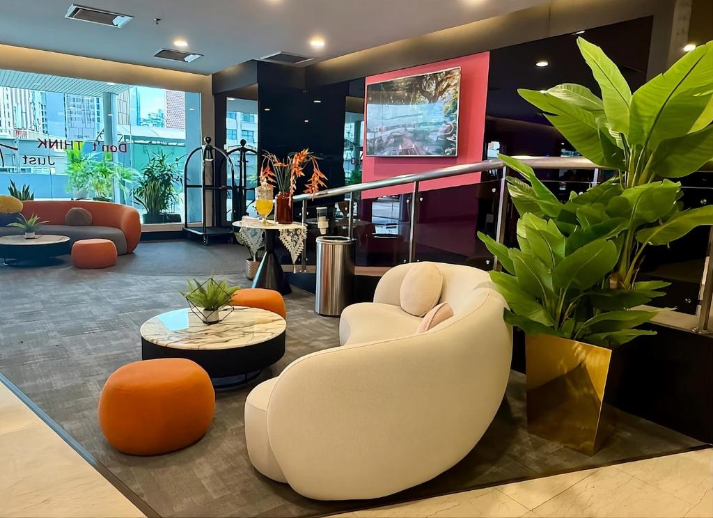 a lobby with orange and white chairs and plants at Apex by Bukit Bintang Hotel in Kuala Lumpur