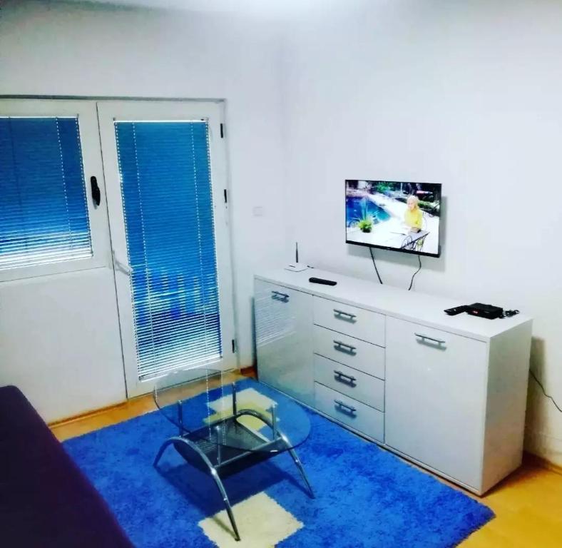 a living room with a glass table and a tv on a dresser at Apartman Centar in Foča