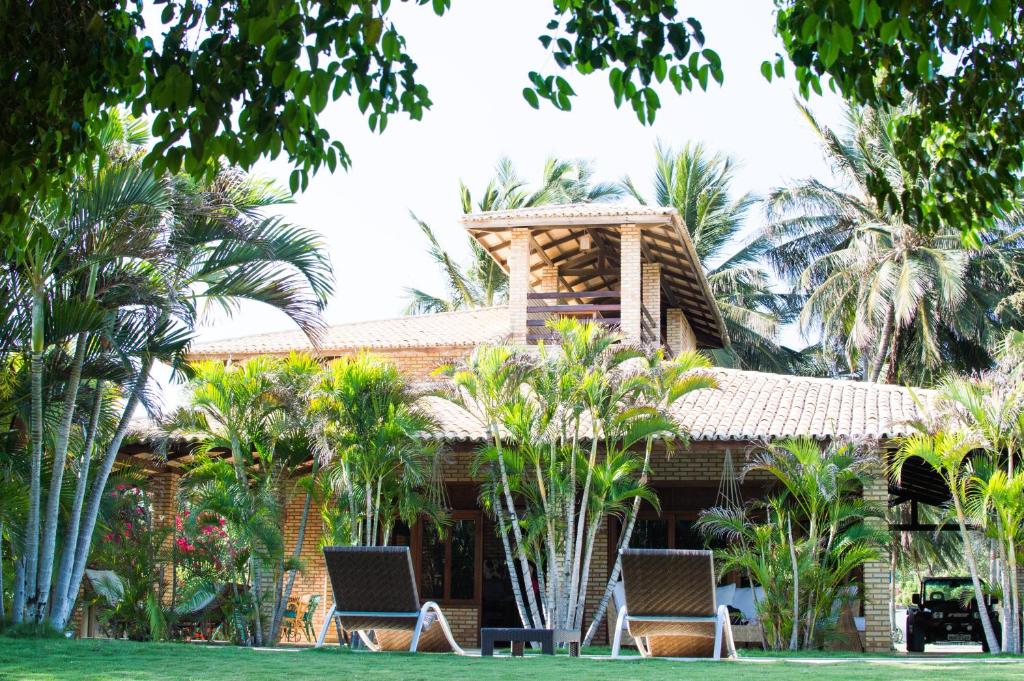 a house with two chairs and palm trees at Refúgios Parajuru - Villa Cristiano in Parajuru