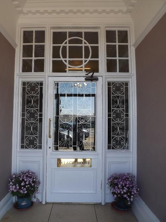 a white door with windows and two vases with purple flowers at Palace Hotel - Small Hotel in Oban