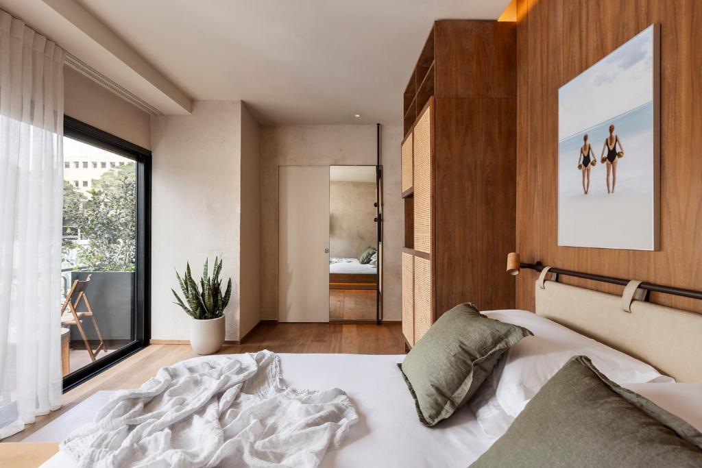 a bedroom with a bed and a large window at The ABY in Tel Aviv