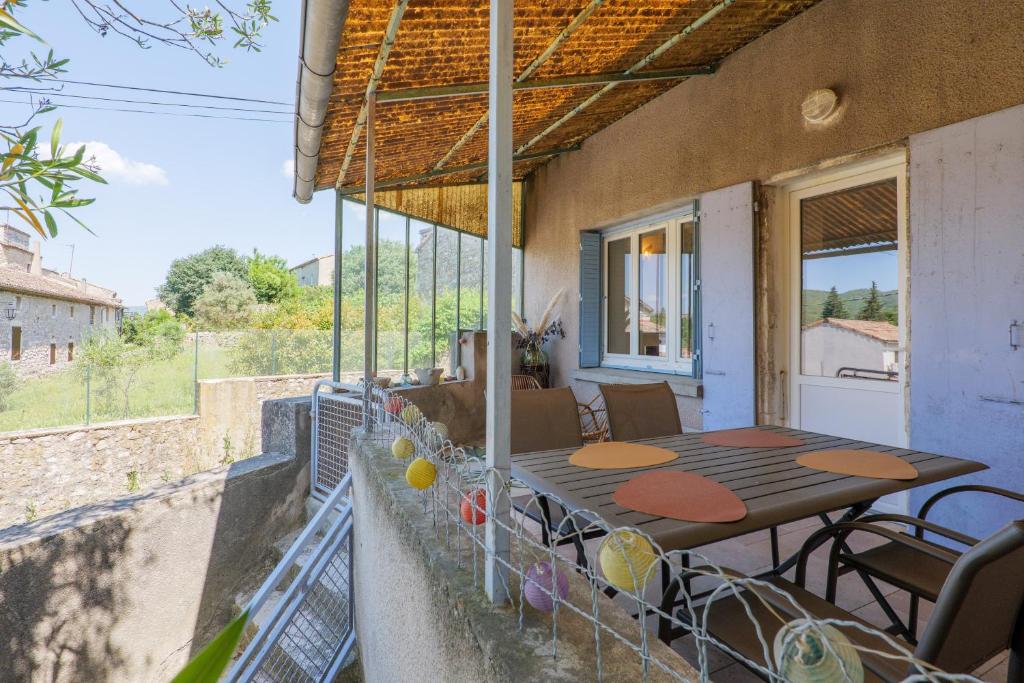 a patio with a table and chairs on a balcony at Charmante Maison Vallon pont d'Arc in Vallon-Pont-dʼArc