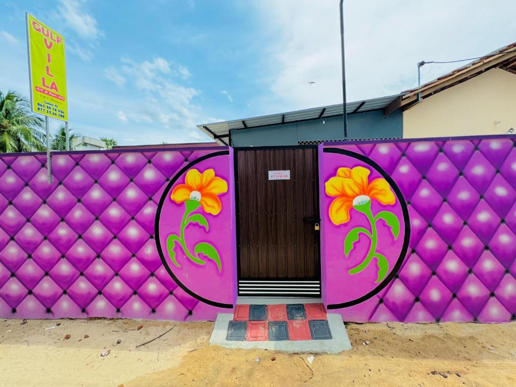 a purple fence with a door with flowers on it at Gulf Villa in Kattankudi