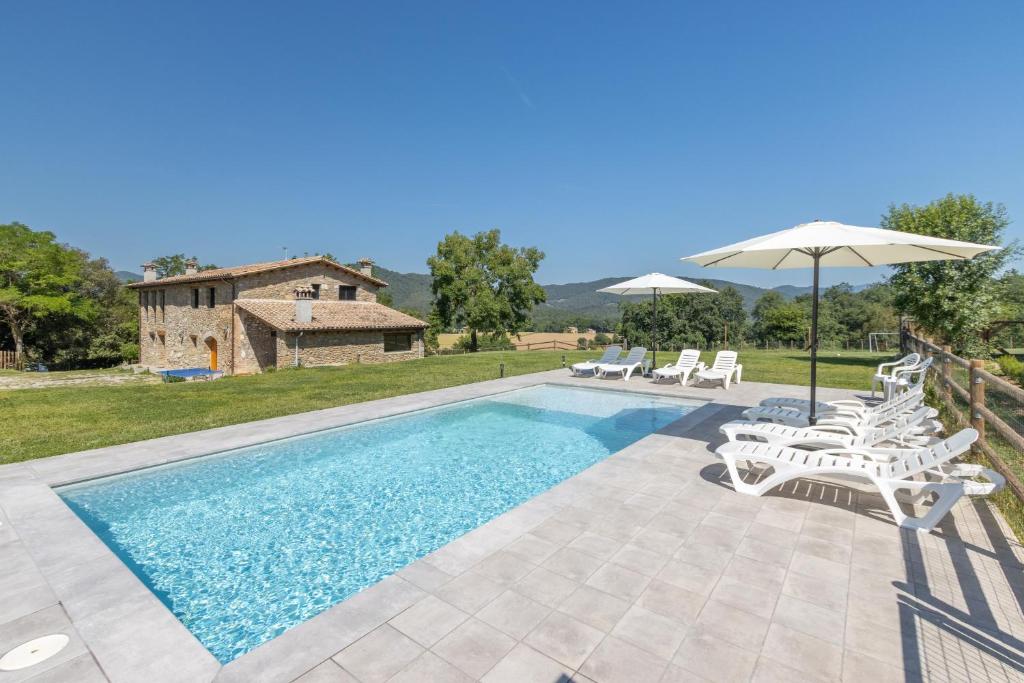 a pool with chairs and umbrellas in front of a house at Mas Ca la Rossa in Girona