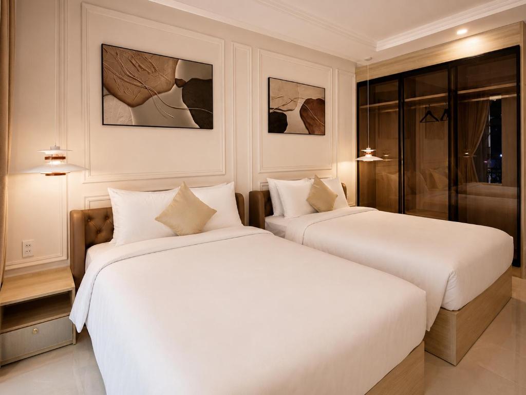 two beds in a hotel room with white sheets at Maison Hin in Hoi An
