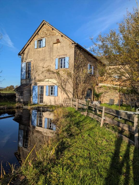 an old stone house next to a body of water at Saisonnée - Gîtes de Charme en Aveyron in Centrès