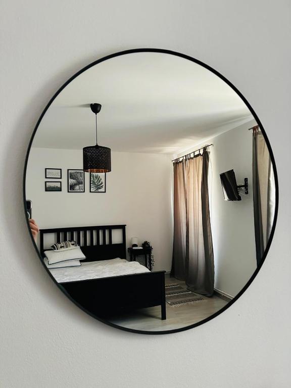 a mirror reflecting a bedroom with a bed in it at Casuta de pe Eminescu in Oraviţa