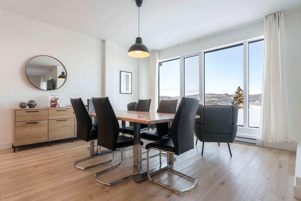 a dining room with a table and black chairs at Luxury Condo with Stunning View and Pool in Baie-Saint-Paul