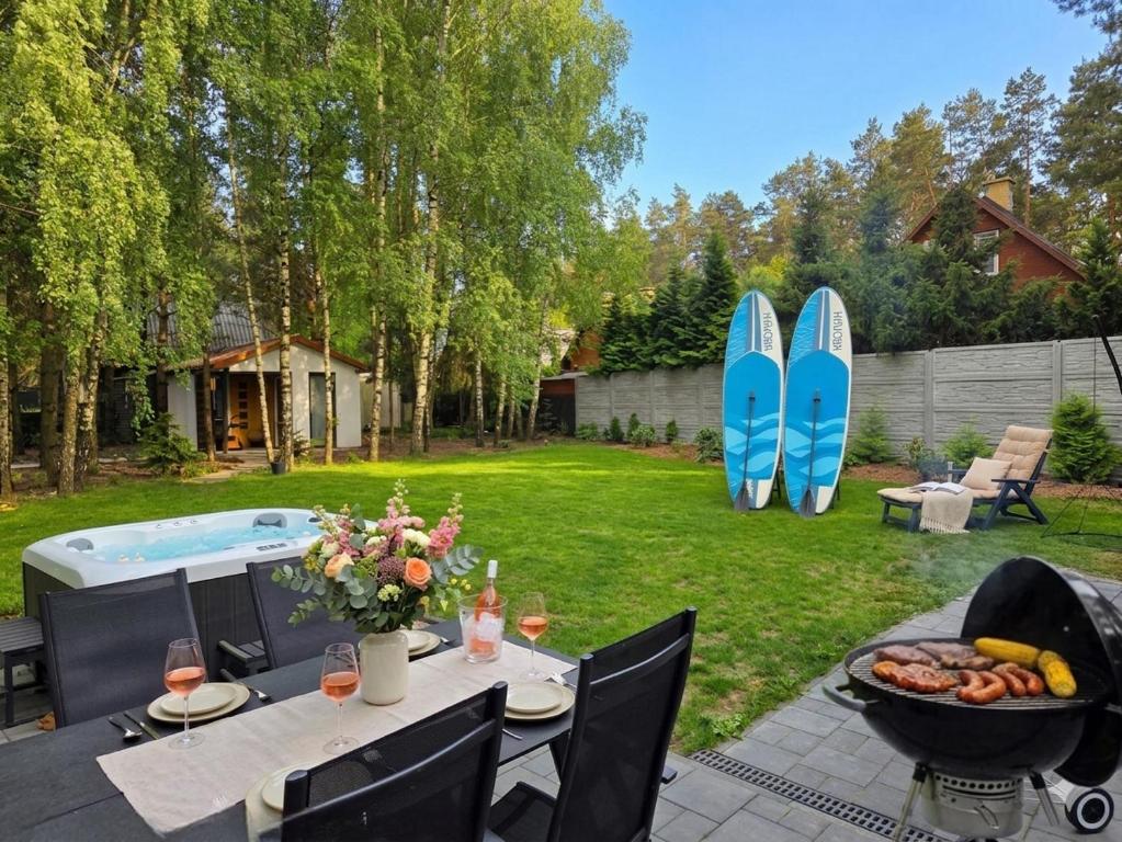 a backyard with a table with a bowl of fruit and surfboards at SAN ESCOBAR sauna jacuzzi jezioro in Rogowo
