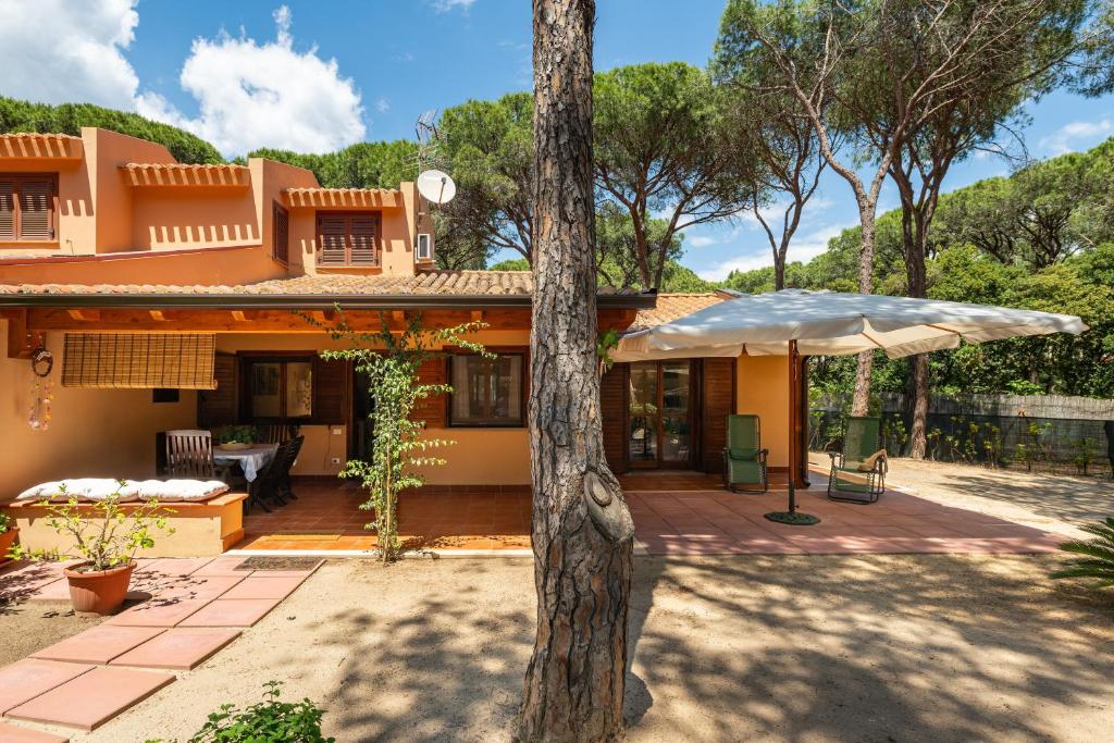 a house with an umbrella and a patio at Villetta Pineta in Santa Margherita di Pula