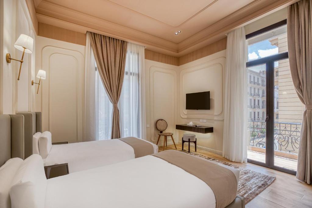two beds in a hotel room with a window at Malak Palace Cairo Hotel in Cairo