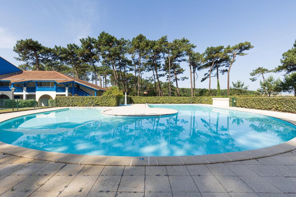 a large swimming pool with a table in the middle at La Canopée - Conciergerieland in Soustons