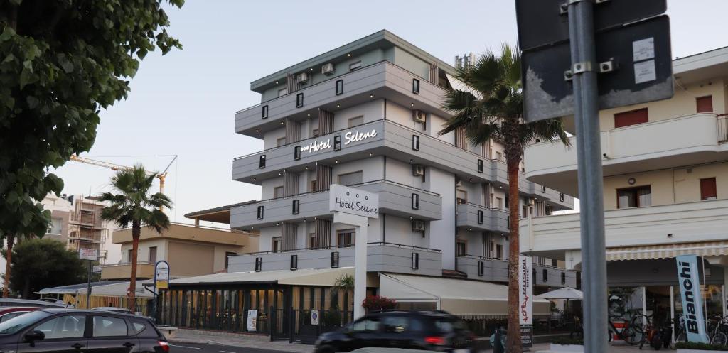 a tall white building on a city street with cars at Hotel Ristorante Selene in Alba Adriatica