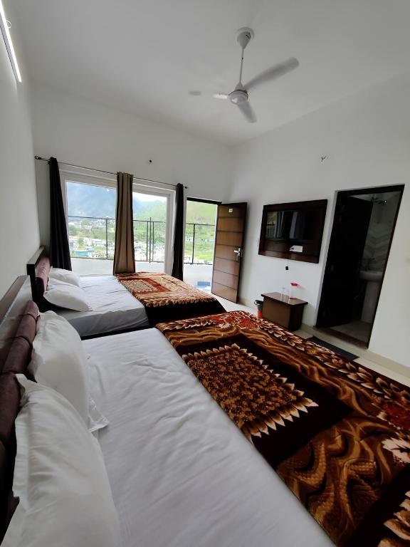 a large bedroom with two beds and a large window at Hotel Riversight in Uttarkāshi