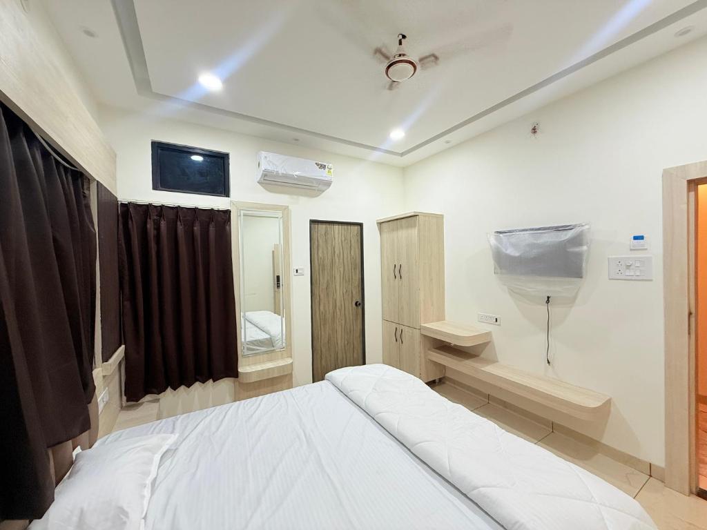 a bedroom with a white bed and a bathroom at Shri Gopal Durga Dham Hotel And Restaurant in Ujjain
