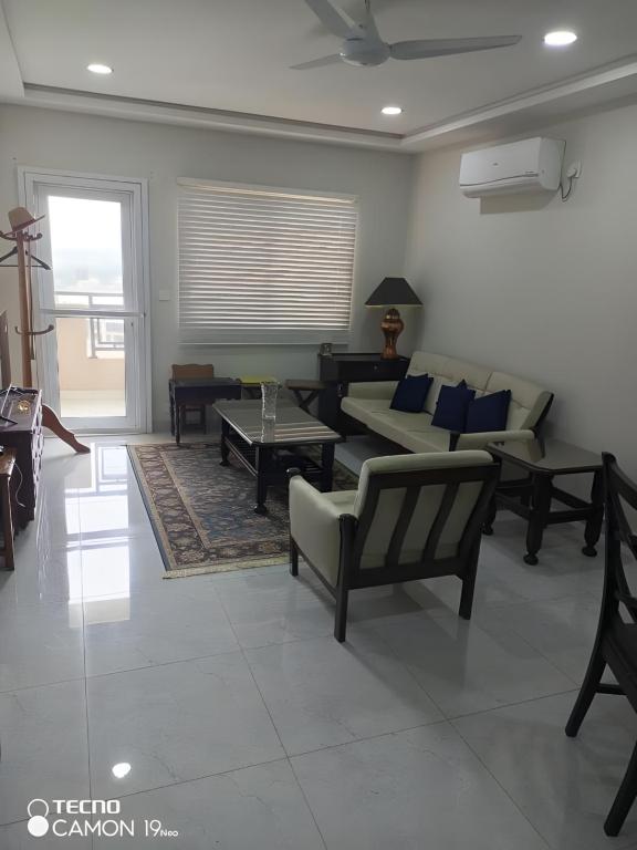 a living room with couches and tables and a window at Margalla Hills View Apartment Islamabad in Islamabad