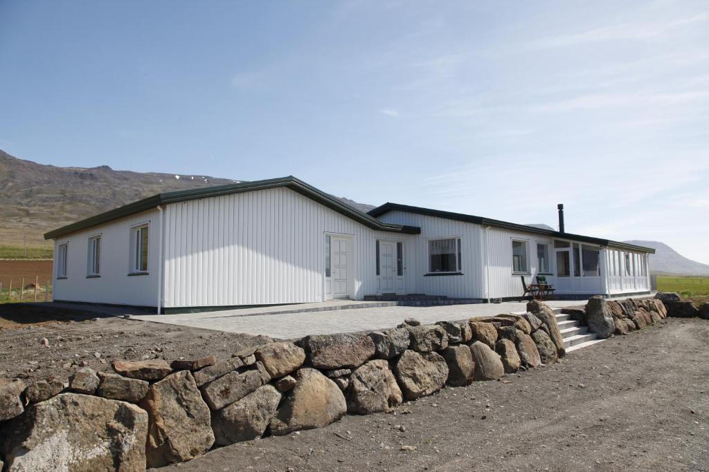 a white house with a stone wall in front of it at Hofsstadir Farmhouse in Hofstaðir
