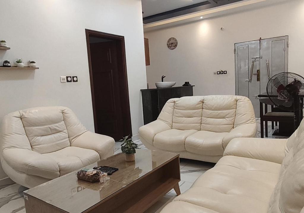 a living room with two white chairs and a coffee table at Appartement Une Chambre Salon Ouando - SKYFORCE in Porto-Novo