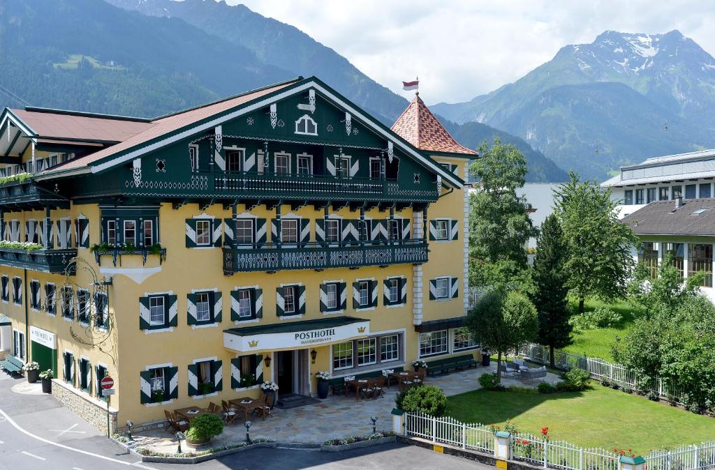 a large yellow and green building with mountains in the background at Posthotel Mayrhofen in Mayrhofen