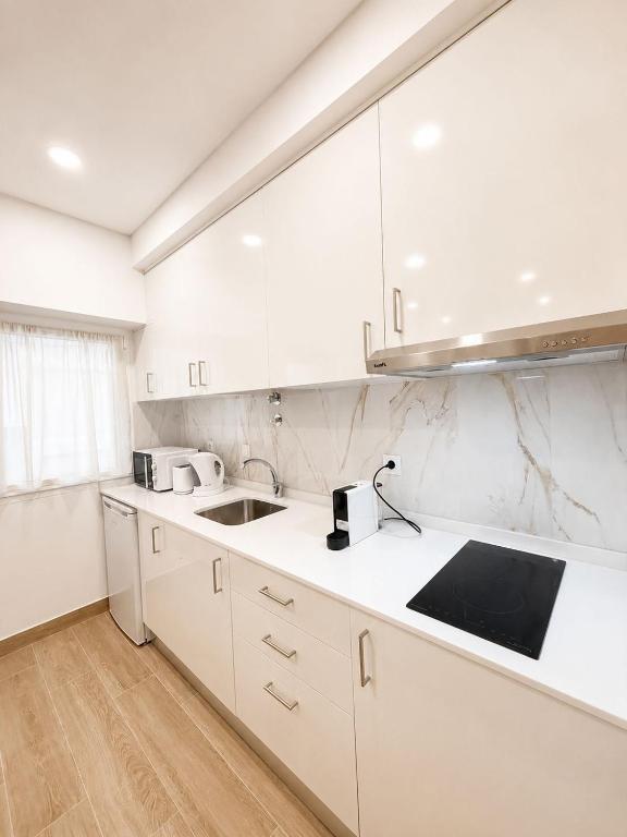 a white kitchen with white cabinets and a sink at Casa Rabiosa in Nazaré