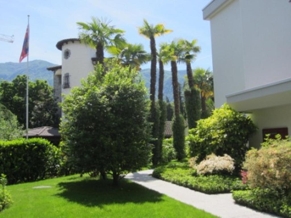 einen Garten mit Palmen und ein Gebäude in der Unterkunft Residenz al Parco in Ascona