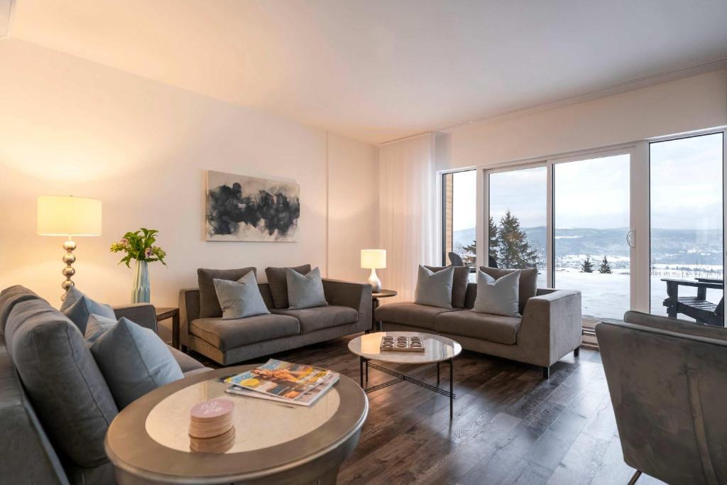 a living room with couches and a table at Chic Condo - River View & Comfort with Pool in Baie-Saint-Paul