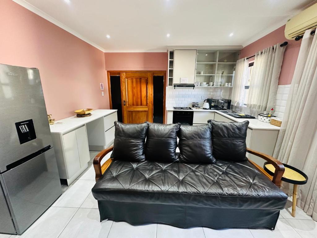 a living room with a couch and a kitchen at Little Haven Conerstone cottage in Windhoek