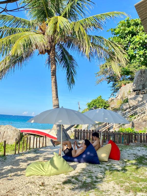 a group of people laying on the beach under umbrellas at Lemon Grass Chalets in Kampong Pasir Panjang