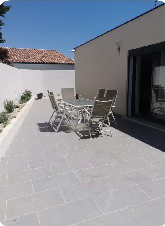 a patio with a table and chairs on a patio at Belle villa à la mer in Sérignan