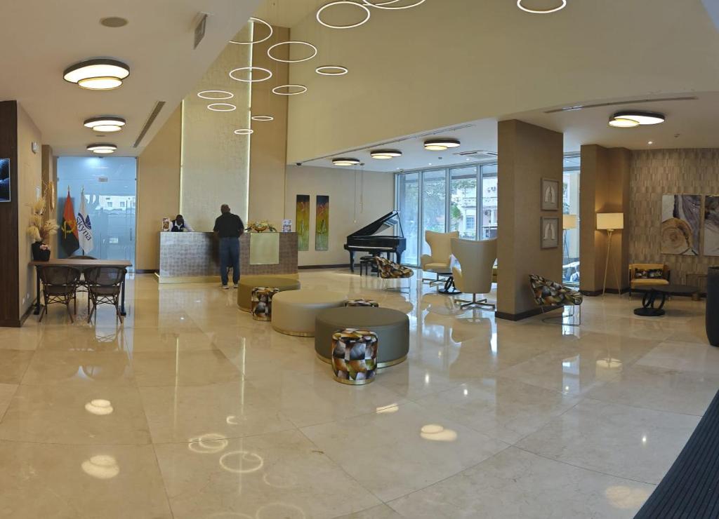 a man standing in a lobby with a piano at Skyna Hotel Luanda in Luanda