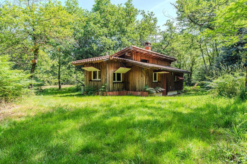a small wooden house in a field of grass at La palombière in Saint-Symphorien