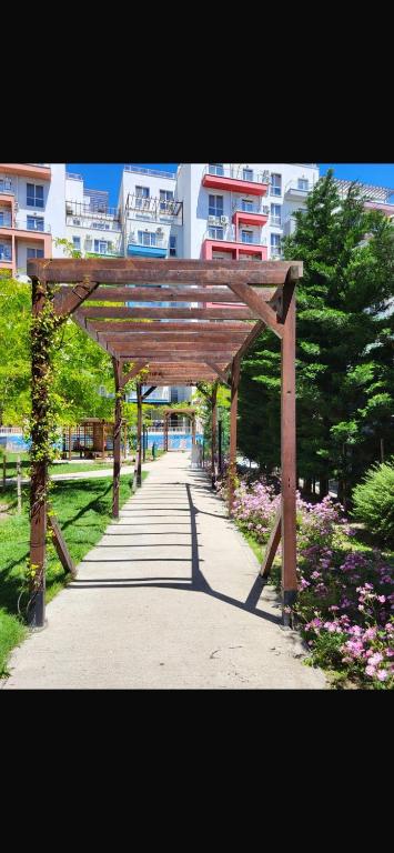 a wooden arch in a park with flowers and buildings at Charming One-Bedroom Flat in Green Diamond in Tbilisi City