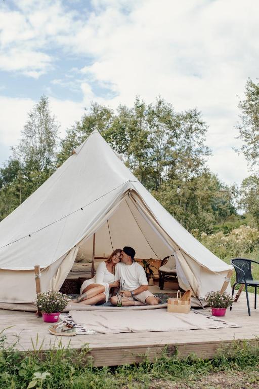 a man and woman sitting in a white tent at Täheonni Glämping in Tautsa