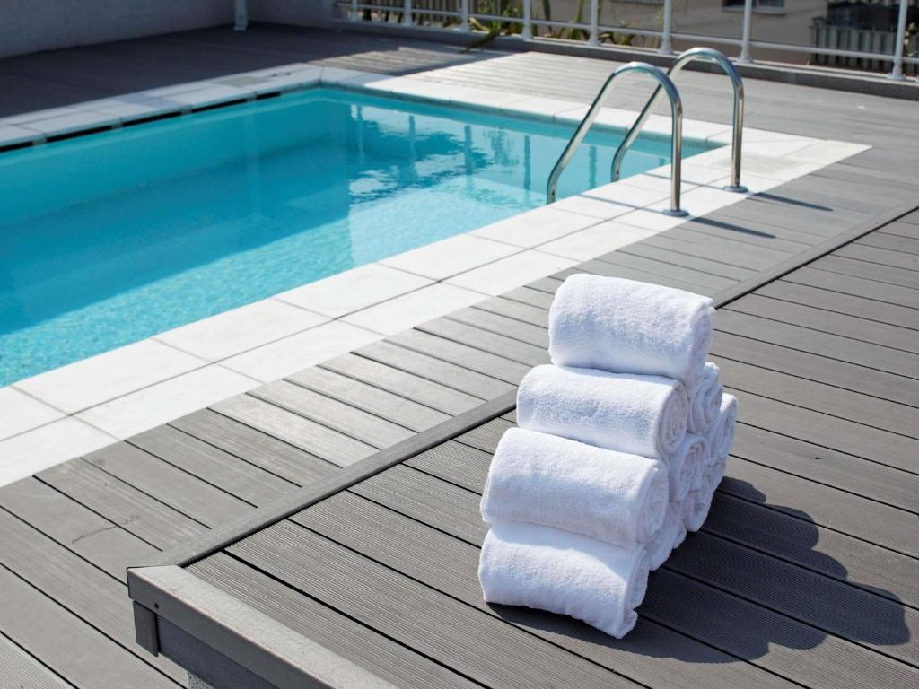 a stack of towels sitting next to a swimming pool at Adagio Nice Centre in Nice