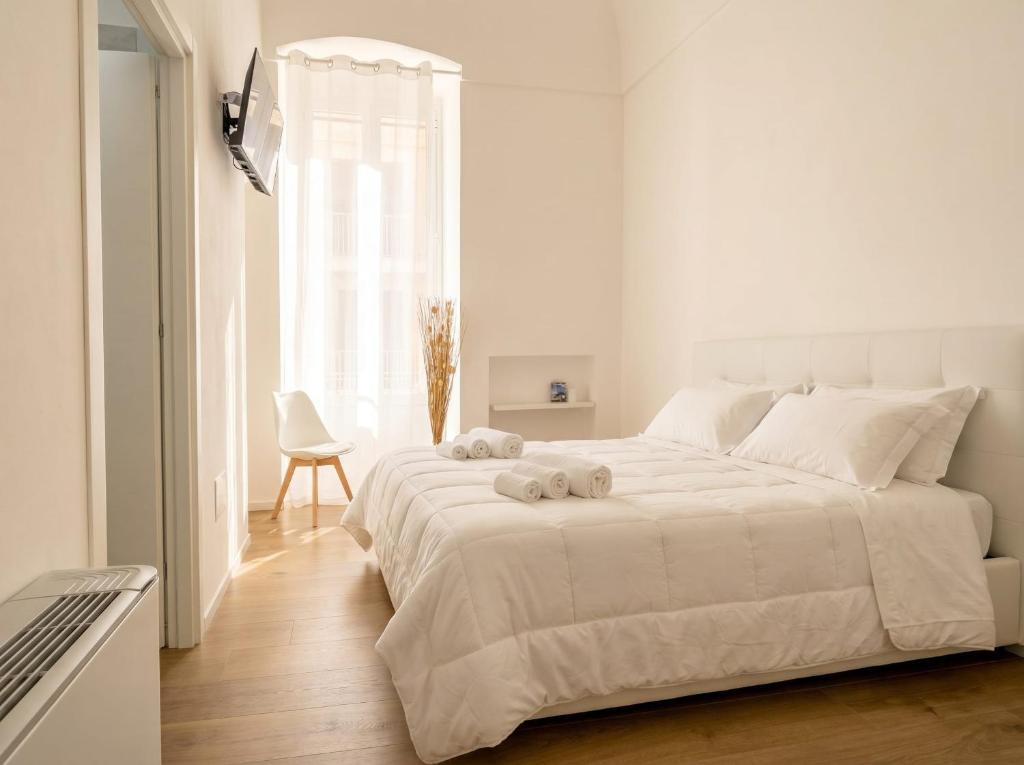 a white bedroom with a large bed with two stuffed animals on it at Casa Del Barone Suites in Monopoli
