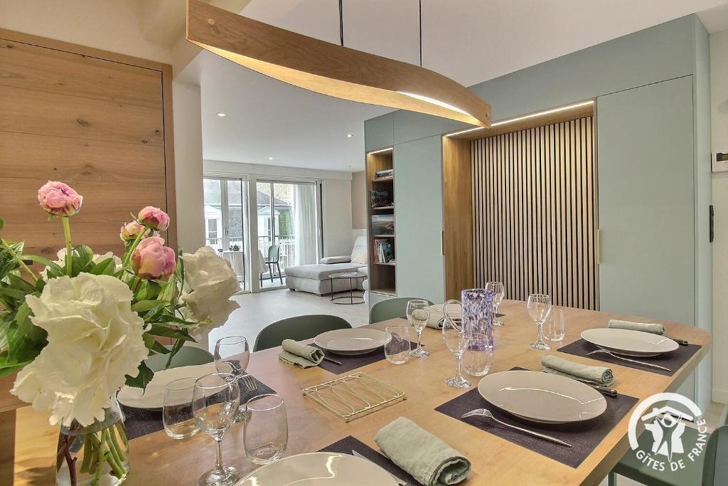 a dining room with a table with flowers and glasses at Ker helios in Dinard